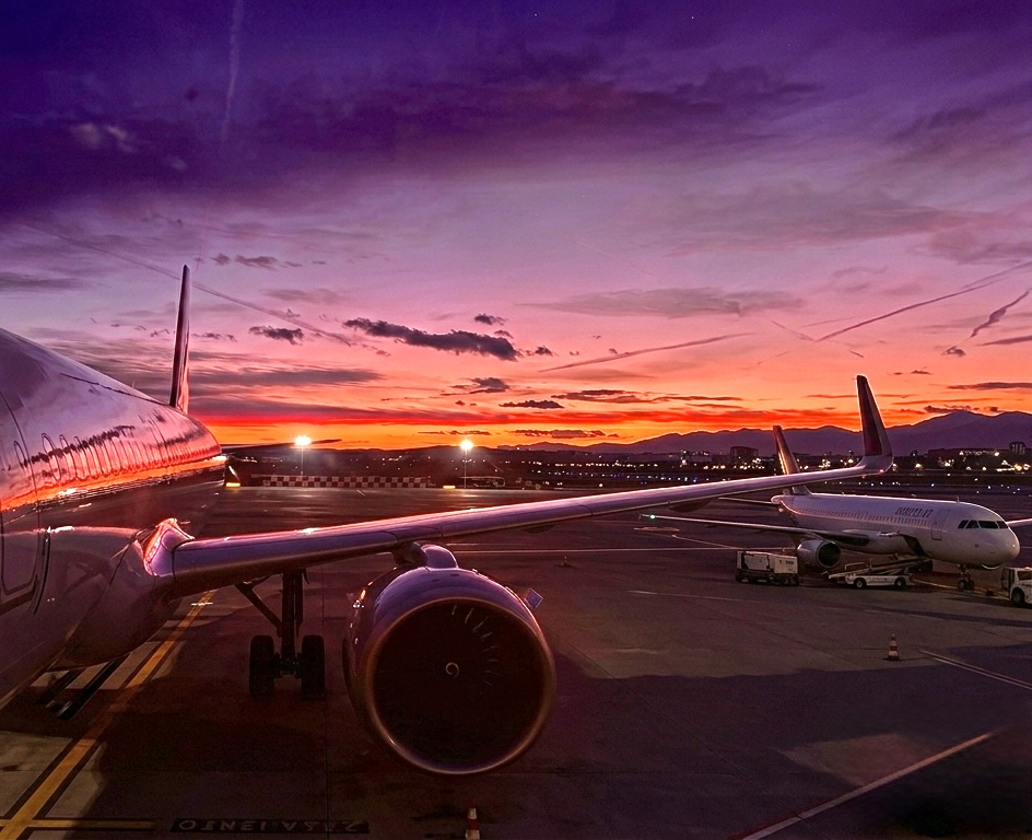 Aerei sulla pista di un aeroporto al tramonto, simbolo di partenze organizzate da un'agenzia di viaggi